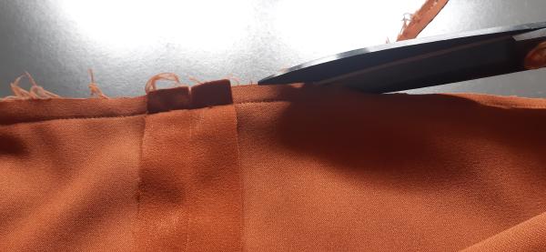 Découpage du surplus de tissu après couture. Cela permet aux bords du vêtement d'être <i>bien plats</i> lorsqu'il est retourné.