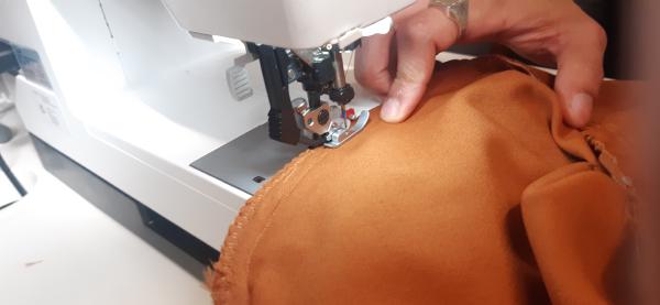 Surjet des emanchures qui comprennent, à ce stade, la <b>doublure</b>, la <b>couche externe</b> et le tissu des <b>manches</b>. Le surjet maintient tout cela pour que le tissu ne s'effiloche pas à l'intérieur.